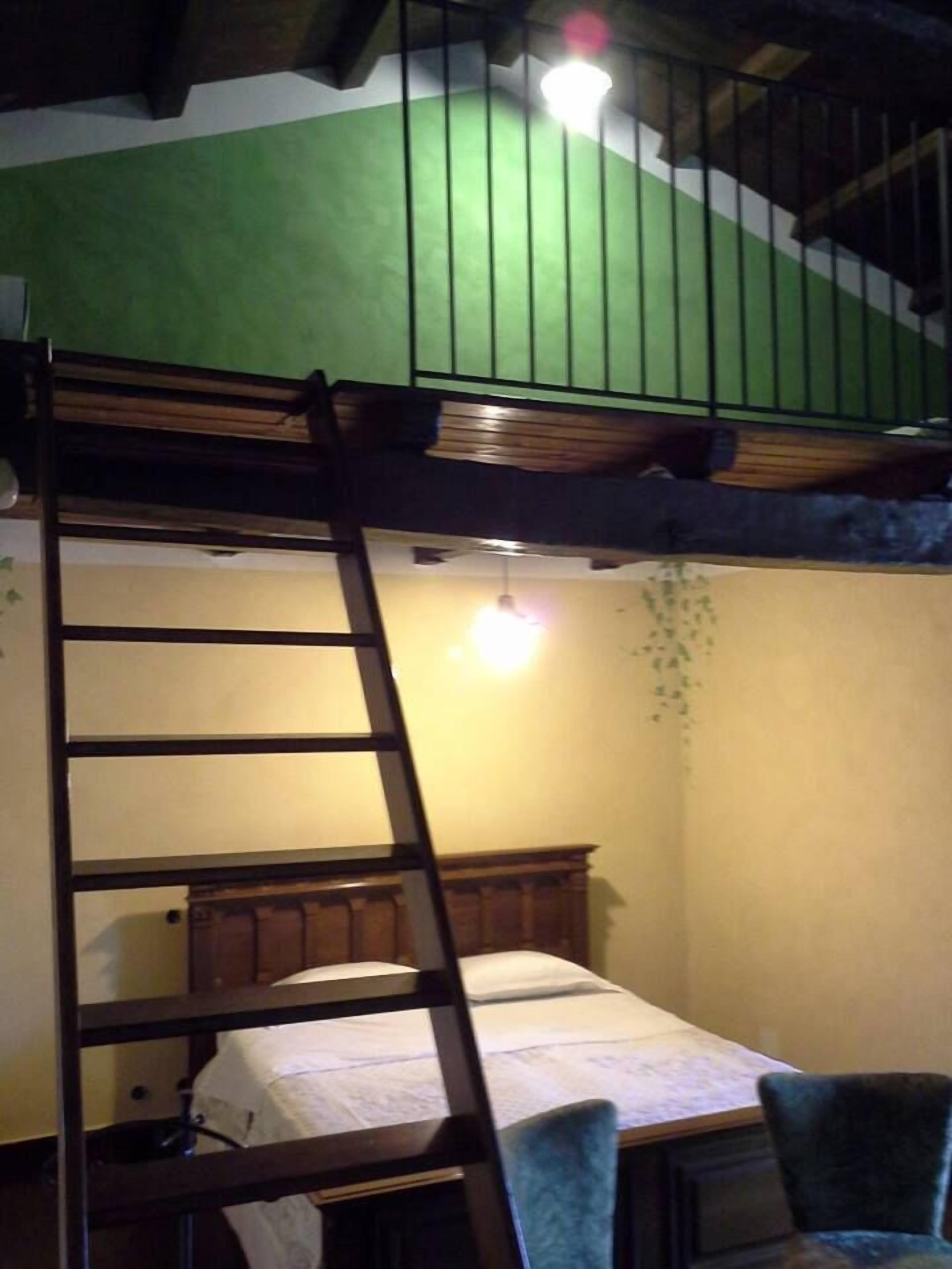 Uma cama beliche com escada, uma cama de solteiro embaixo e uma cadeira.