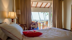 A hotel room with a bed, a desk, and a view of the beach. - Arhimser Villa (Kahandamodara)