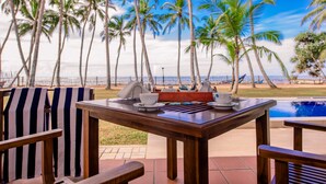 A wooden table with a view of palm trees and a pool. - Arhimser Villa (Kahandamodara)