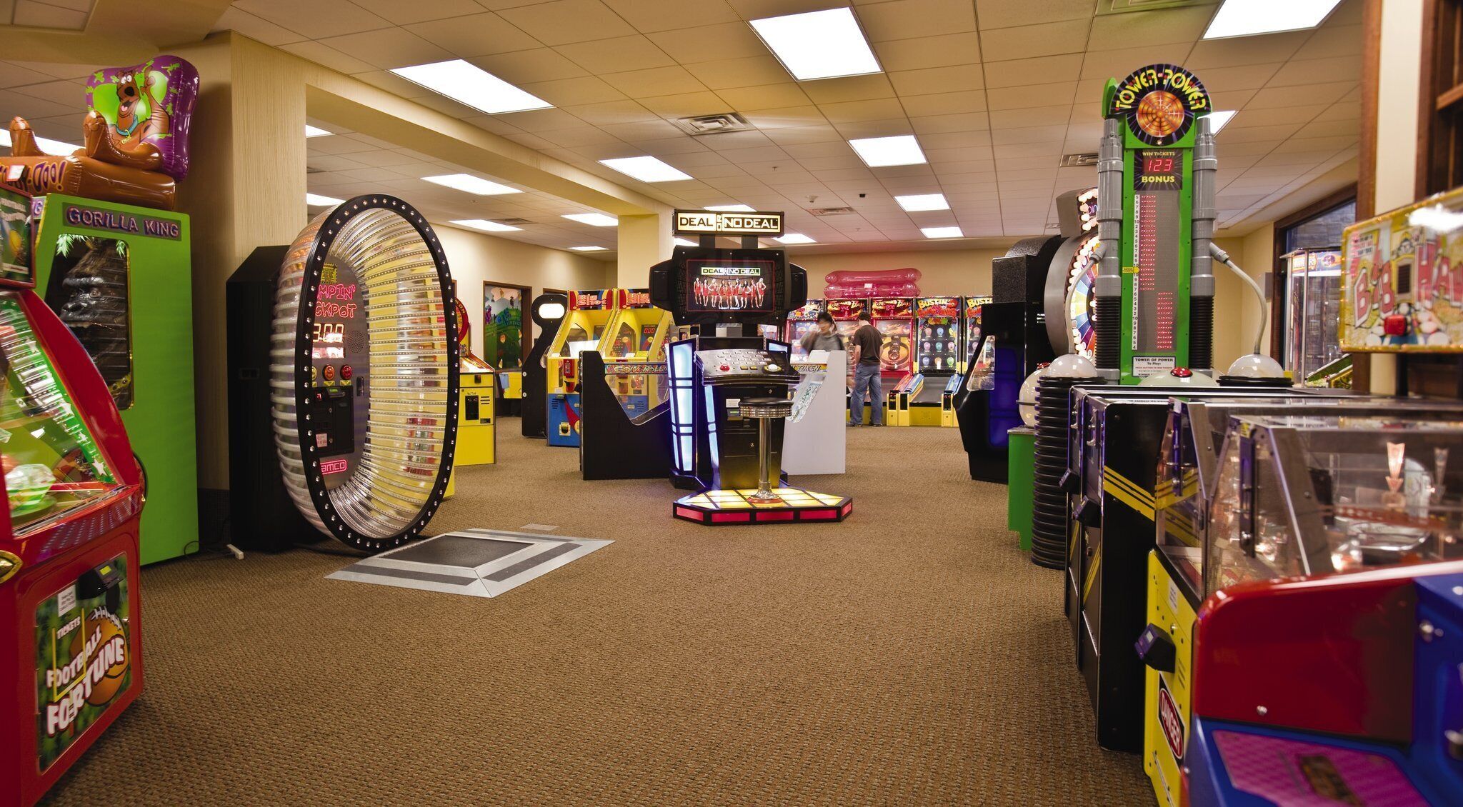 A variety of arcade games in a brightly lit indoor space with a carpeted floor.