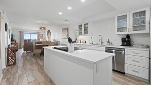 Una cocina moderna con armarios blancos, una isla central y un comedor con vistas.