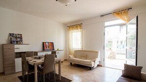 Un salon moderne comprenant un coin repas, un canapé et une grande porte-fenêtre coulissante donnant sur un espace extérieur.