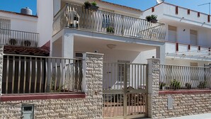 Un immeuble résidentiel de deux étages, doté d’une façade en pierre, d’une entrée sécurisée et de balcons avec des garde-corps en métal.