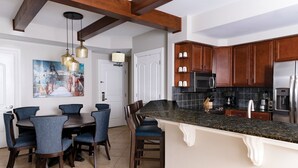 A kitchen with dark wooden cabinets, a granite countertop, and a stainless steel refrigerator.