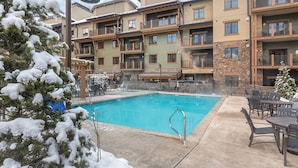 Un hotel de diverses plantes amb piscina, zona de seients a l'exterior i arbres coberts de neu.