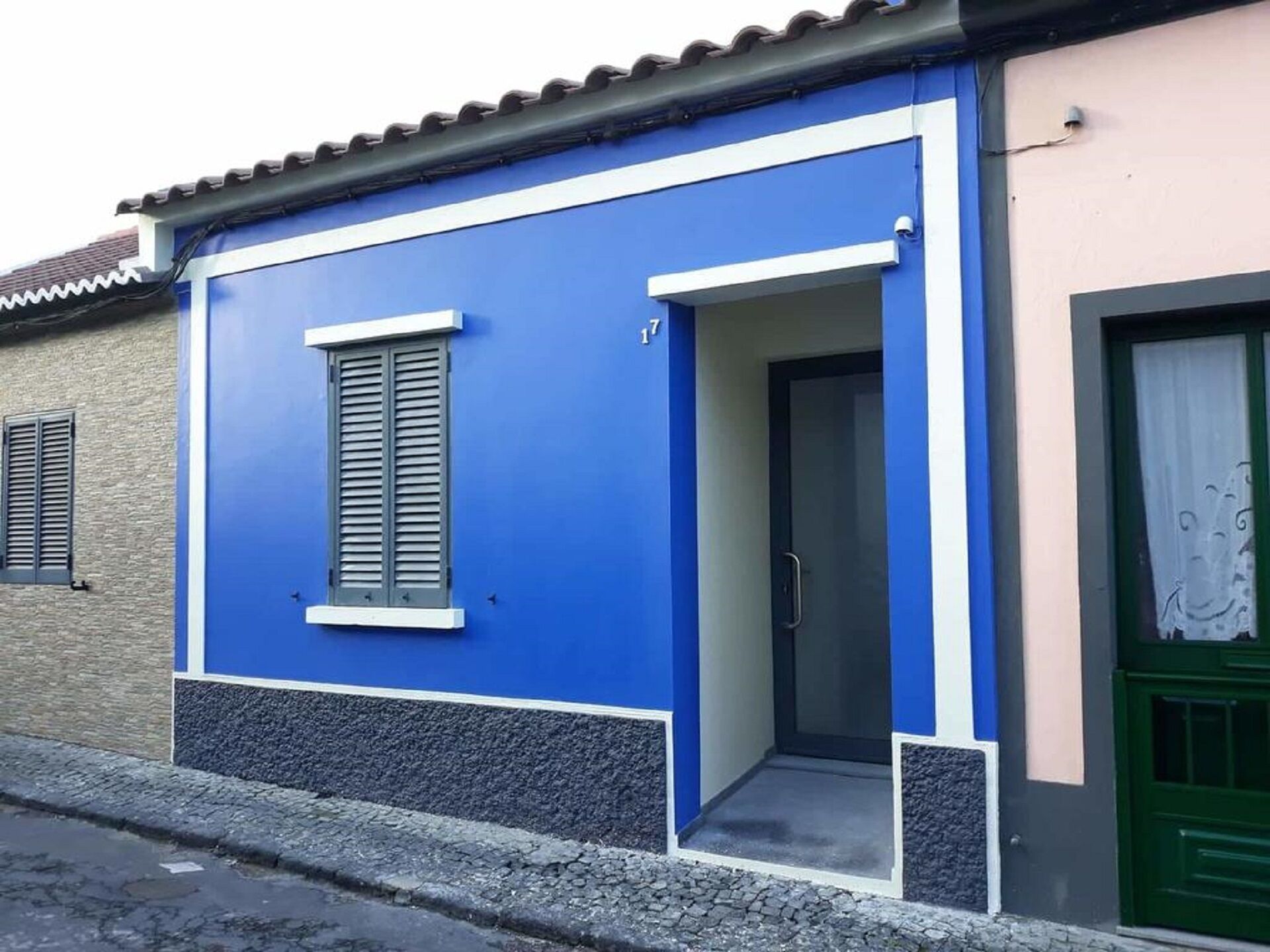Un bâtiment à la façade bleue, avec une porte et une fenêtre dotée de volets.