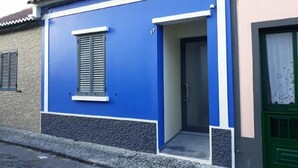 A building with a blue facade, a door, and a window with shutters. - California House in Ribeira Grande (Ribeira Grande)