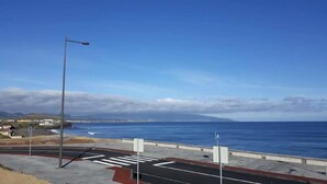 A coastal road with a pedestrian crossing and a blue sign. - California House in Ribeira Grande (Ribeira Grande)