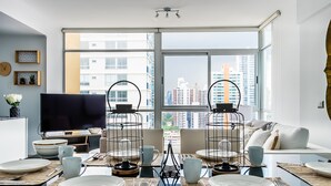 A modern dining area with a large window, a flat-screen TV, and a sofa.