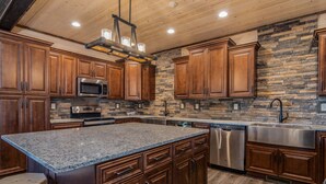 A kitchen with wooden cabinets, a granite countertop, a stone backsplash, stainless steel appliances, and a wooden ceiling. - Private Indoor Pool & Basketball Court Retreat with Arcade Games, Sleeps 50, Free Tickets & Views (Branson)