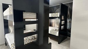 A modern hotel room with bunk beds, a large mirror, and a patterned bedspread.