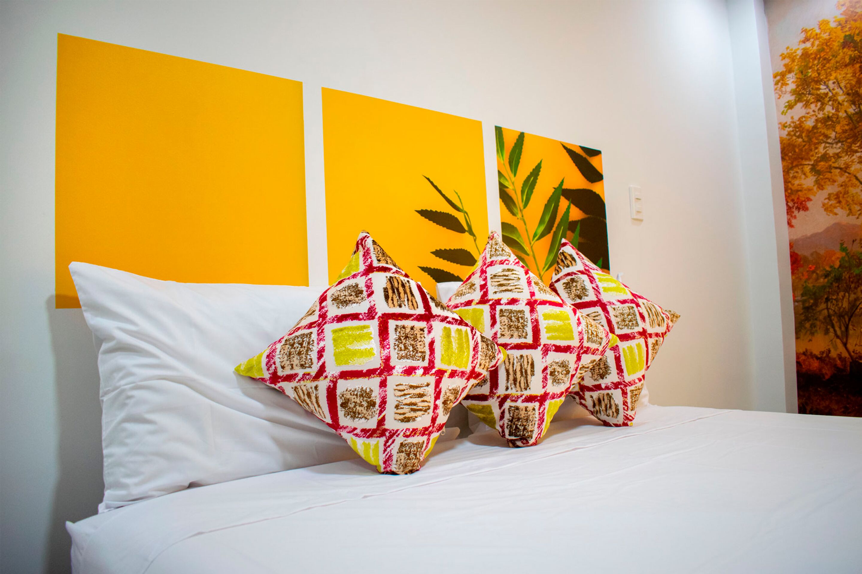 Un lit avec une literie blanche et deux coussins décoratifs à motifs géométriques.