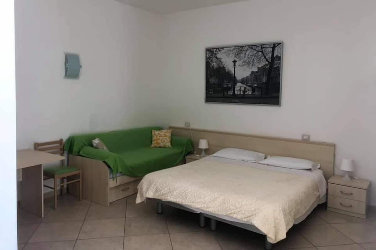 A bedroom with a bed, bedside tables, a desk, and a chair.