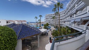 Un resort con varios balcones, zonas de estar al aire libre y palmeras.