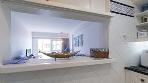 Una cocina con baldosas blancas, una repisa con un cuenco decorativo y una ventana que da a la calle.