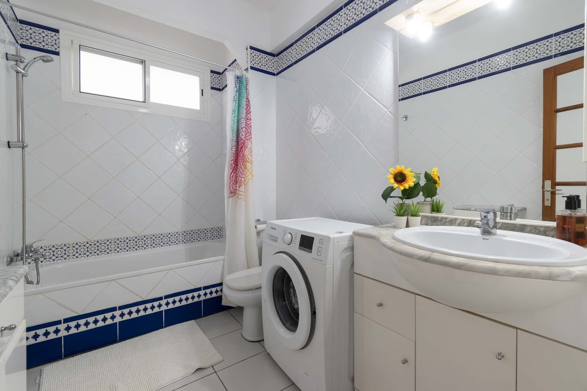 Ein Badezimmer mit Waschmaschine, Waschbecken, Toilette und Dusche.