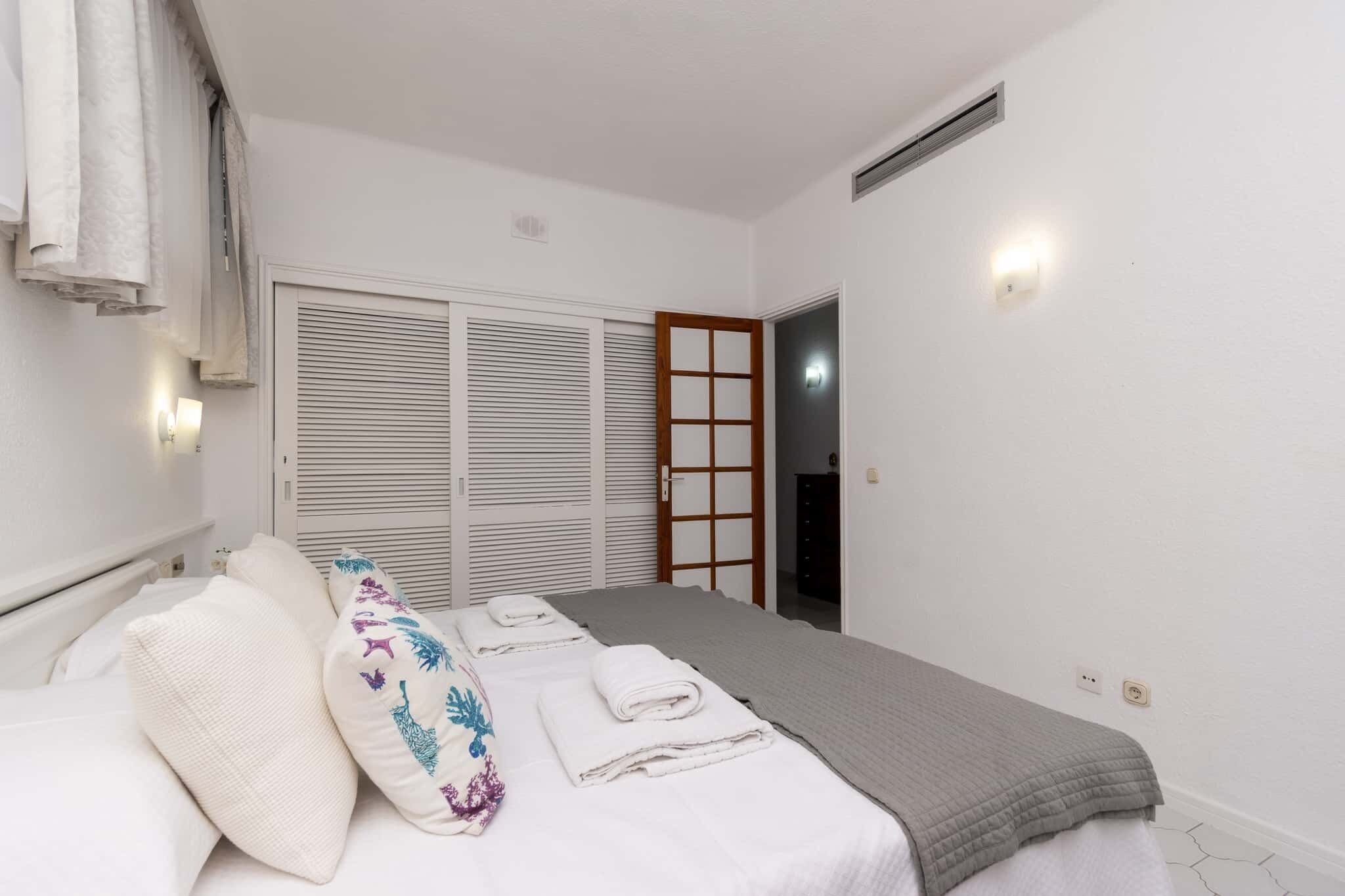 Una camera da letto con un letto, cuscini, un comodino, un armadio e una porta.