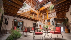 A spacious courtyard with wooden balconies, red cushioned chairs, and potted plants. - Casona Corrales Hotel Boutique (Cusco)