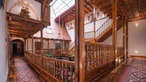 A grand interior with a wooden staircase, ornate railings, and a patterned carpet. - Casona Corrales Hotel Boutique (Cusco)
