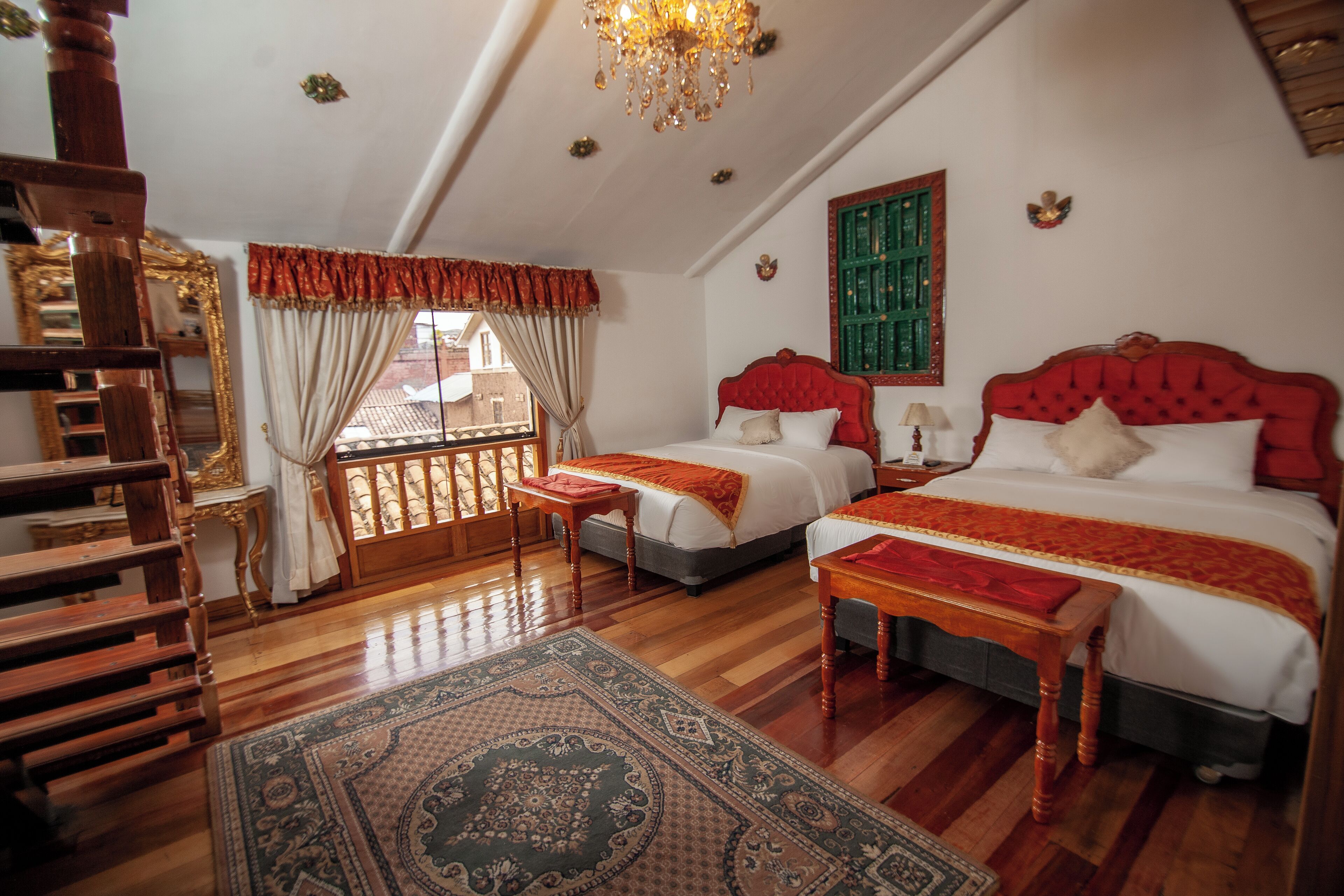 A bedroom with two beds, a wooden floor, a chandelier, and a view of the outside.