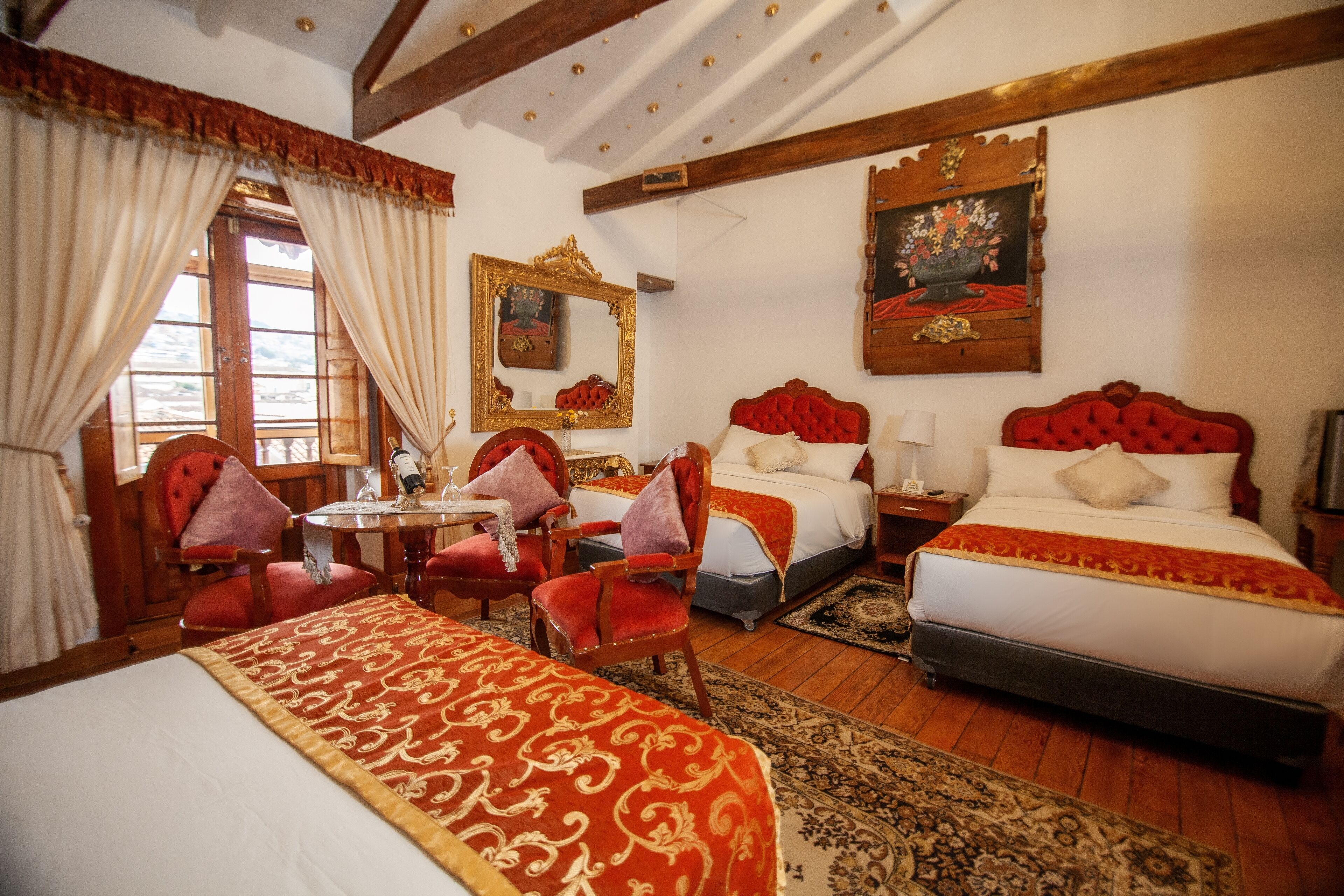 Quarto de hotel com uma cama grande, duas camas menores, uma mesa de jantar e uma cadeira.