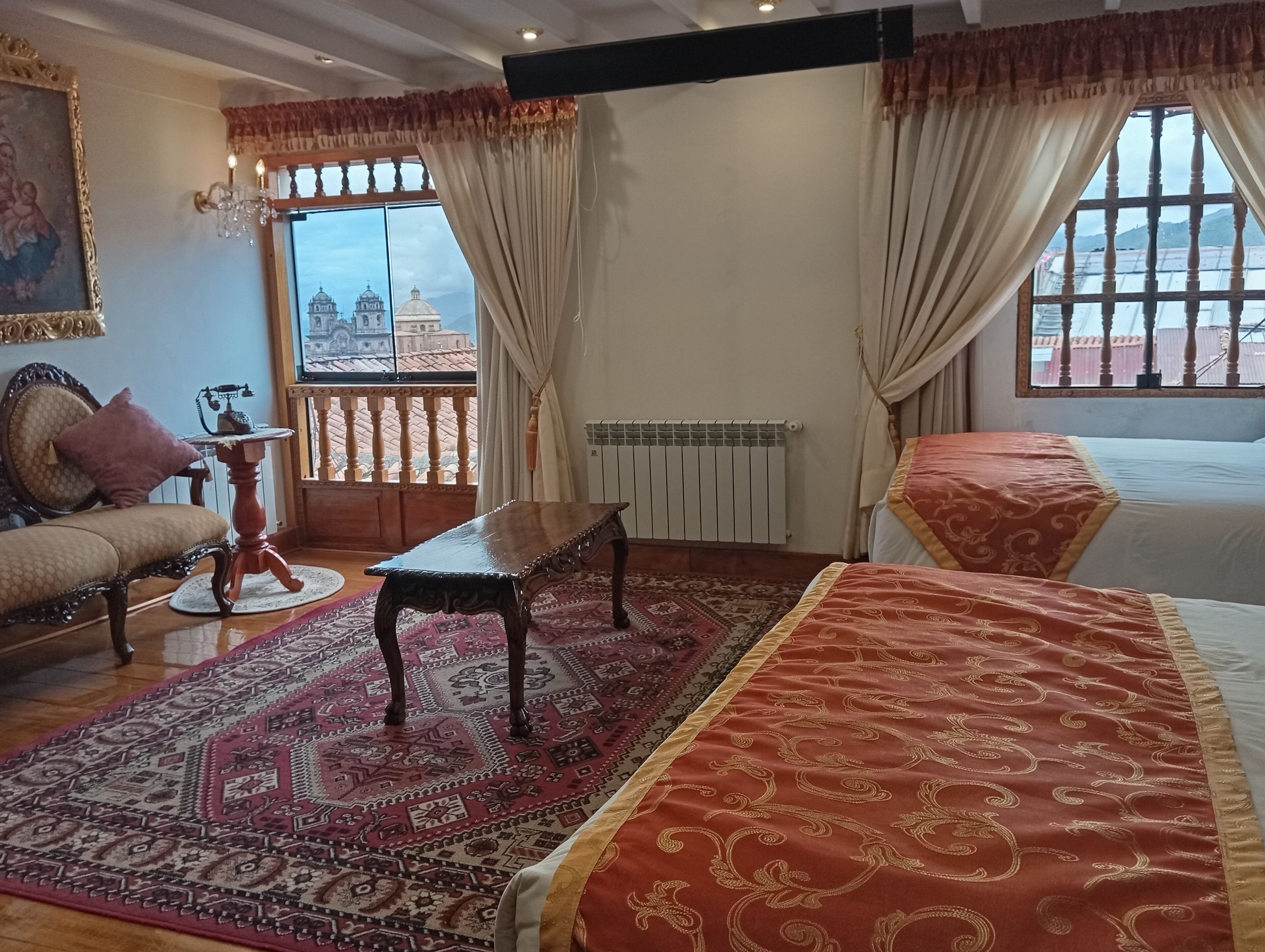 Una habitación con sofá, una mesa, un tapete estampado y vistas a un paisaje urbano a través de amplias ventanas.