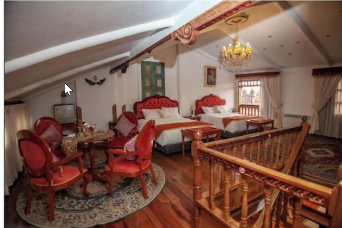 Una habitación tradicional con dos camas, una araña y una escalera de madera.