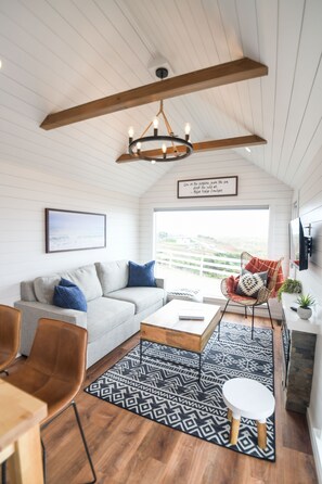 A cozy living room with a grey sofa, a wooden coffee table, and a patterned rug.