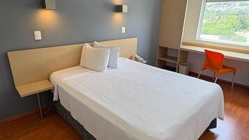 Moderni hotellihuone, jossa on suuri sänky, yöpöydät, työpöytä ja tuoli.