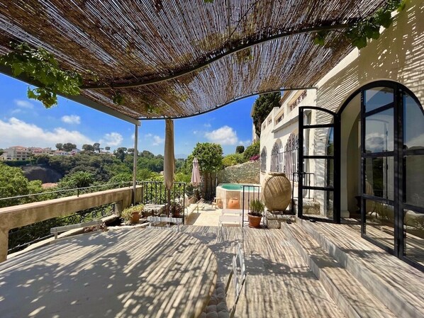 Eine Terrasse mit Pergola, Sitzgelegenheiten im Freien, einem Whirlpool und Blick auf die umliegende Landschaft.