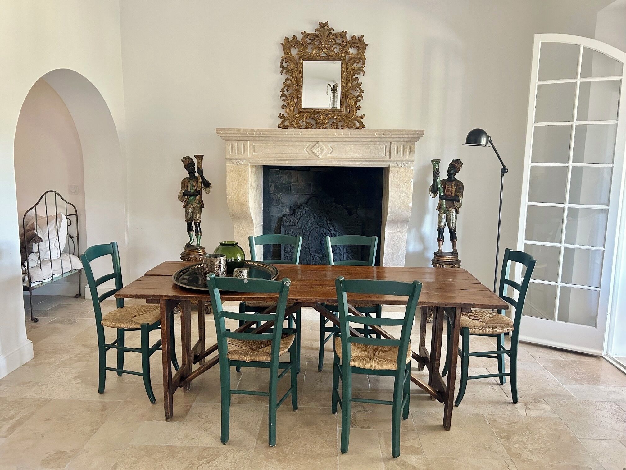 Una sala da pranzo con camino, uno specchio decorato e sedie verdi.
