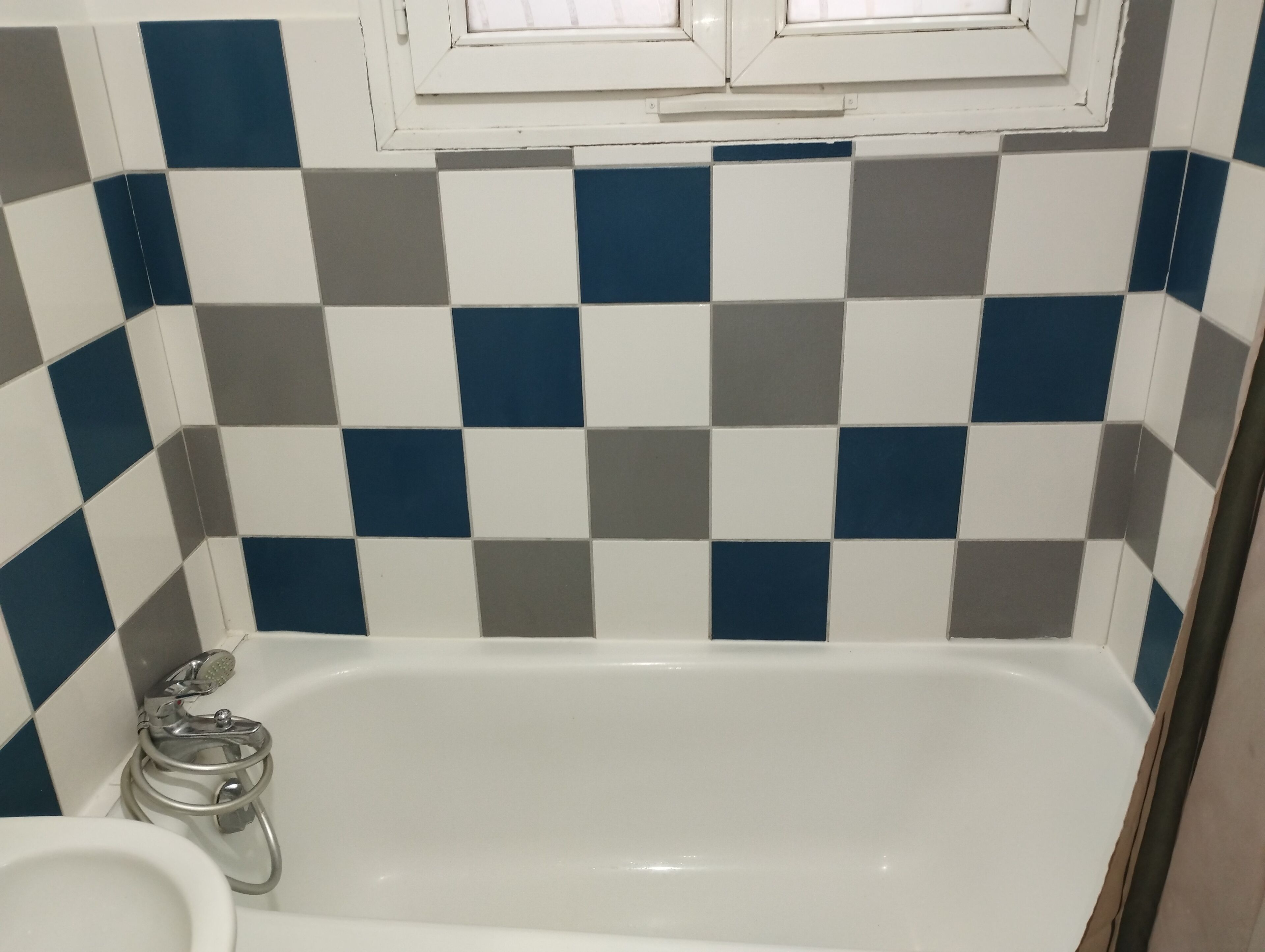 Un baño con pared de baldosas a cuadros, una bañera y un inodoro.