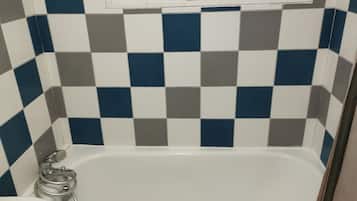 Un baño con pared de baldosas a cuadros, una bañera y un inodoro.