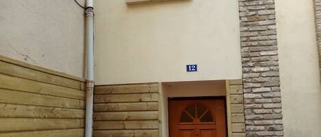A building entrance with a wooden door, a small window, and a number sign indicating the unit number.