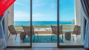 Un balcon agrémenté de fauteuils en osier et d’un tapis à motifs, offrant une vue sur la côte.