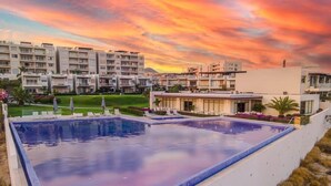 Une piscine offrant une vue sur des immeubles d’habitation et sur le coucher du soleil.