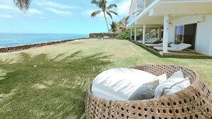 A beachside property with a grassy lawn, a wicker lounge chair, and a view of the ocean. - Feel Hawaii. Magnificent view. Family Reunion Home. Children friendly. (Waianae)