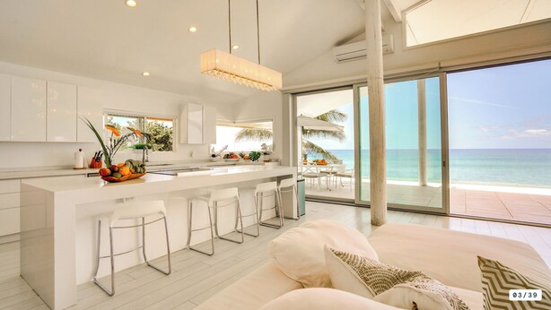 A modern kitchen with a central island, bar stools, and a view of the ocean. - Feel Hawaii. Magnificent view. Family Reunion Home. Children friendly. (Waianae)