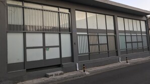 Un bâtiment doté de grandes fenêtres, d’une entrée fermée par un portail et d’un trottoir.