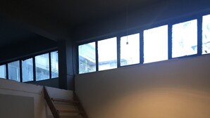 Une pièce avec un escalier en bois, une table entourée de chaises et de grandes fenêtres.