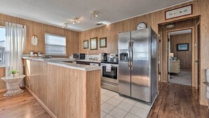 A modern kitchen with wooden paneling, stainless steel appliances, and a small island.