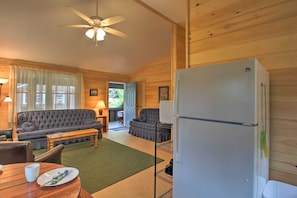 Een gezellig interieur van een chalet met een eethoek, twee banken, een plafondventilator en een koelkast.