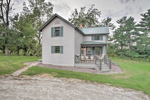 A two-story house with a covered porch and a gravel driveway.