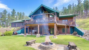 A log cabin with a covered deck, a fire pit, and a stone pathway. - Black Hills Cabin: Hot Tub, Game Room & Deck (Custer)