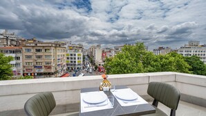 A rooftop terrace with a table set for two, overlooking a cityscape with buildings and a busy street. - Graziella Gold Hotel (Istanbul)