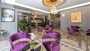 A lobby with purple chairs, a reception desk, and a large painting on the wall. - Graziella Gold Hotel (Istanbul)