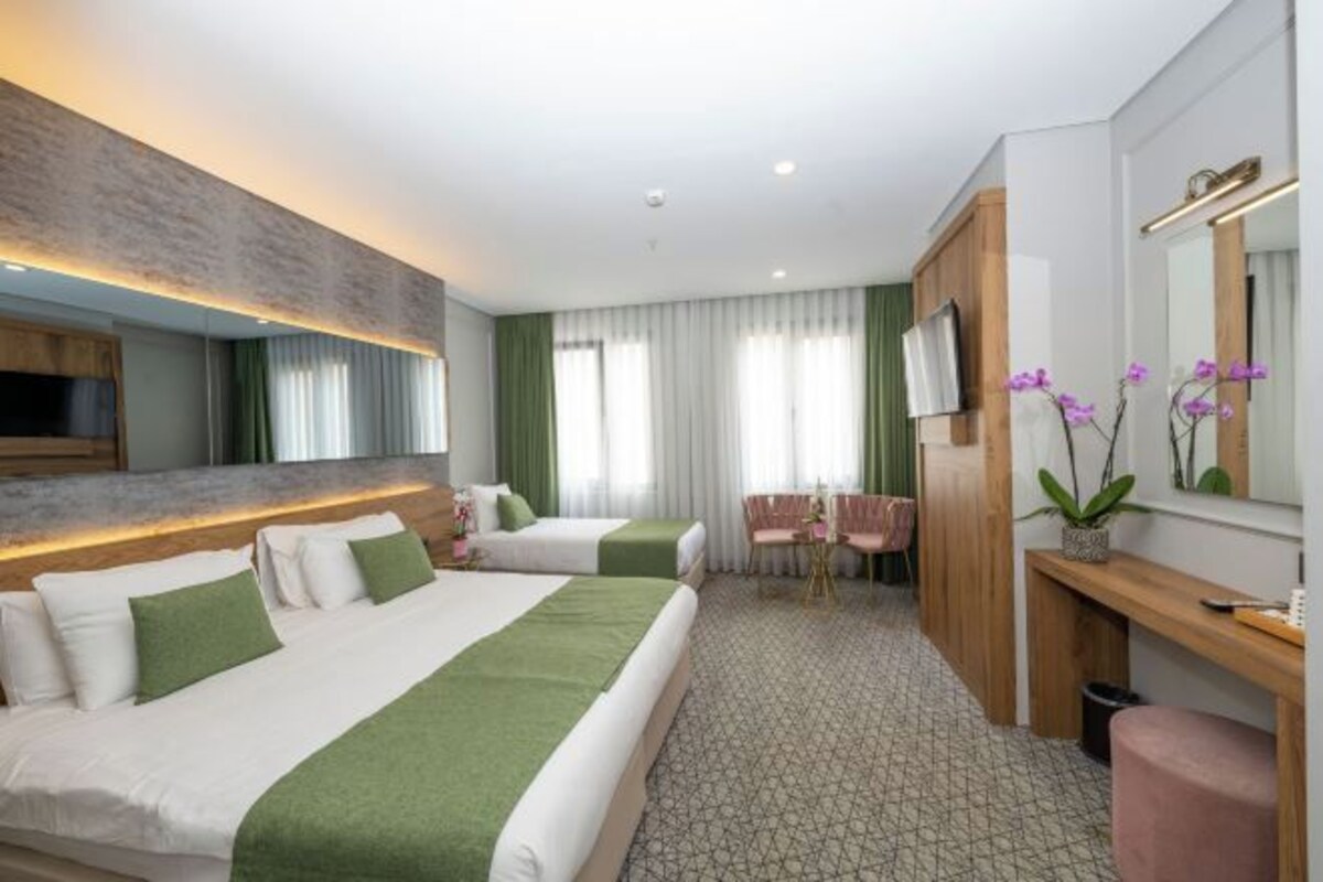 Une chambre d’hôtel avec deux lits, un bureau, une chaise, une télévision et un miroir.