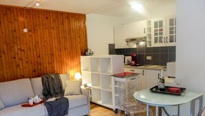 A modern living room with a sofa, a small table, and a kitchen area with cabinets and appliances. - L'Aiguille du Midi by Interhome (Chamonix)