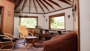 A cozy cabin interior with a wooden ceiling, two windows, a dining table, and a sofa. - Antucalhue (Antuco)