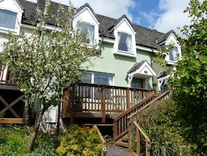 A row of houses with a wooden deck and stairs leading to the entrance. - 14 Tweed Cottage (Jedburgh)